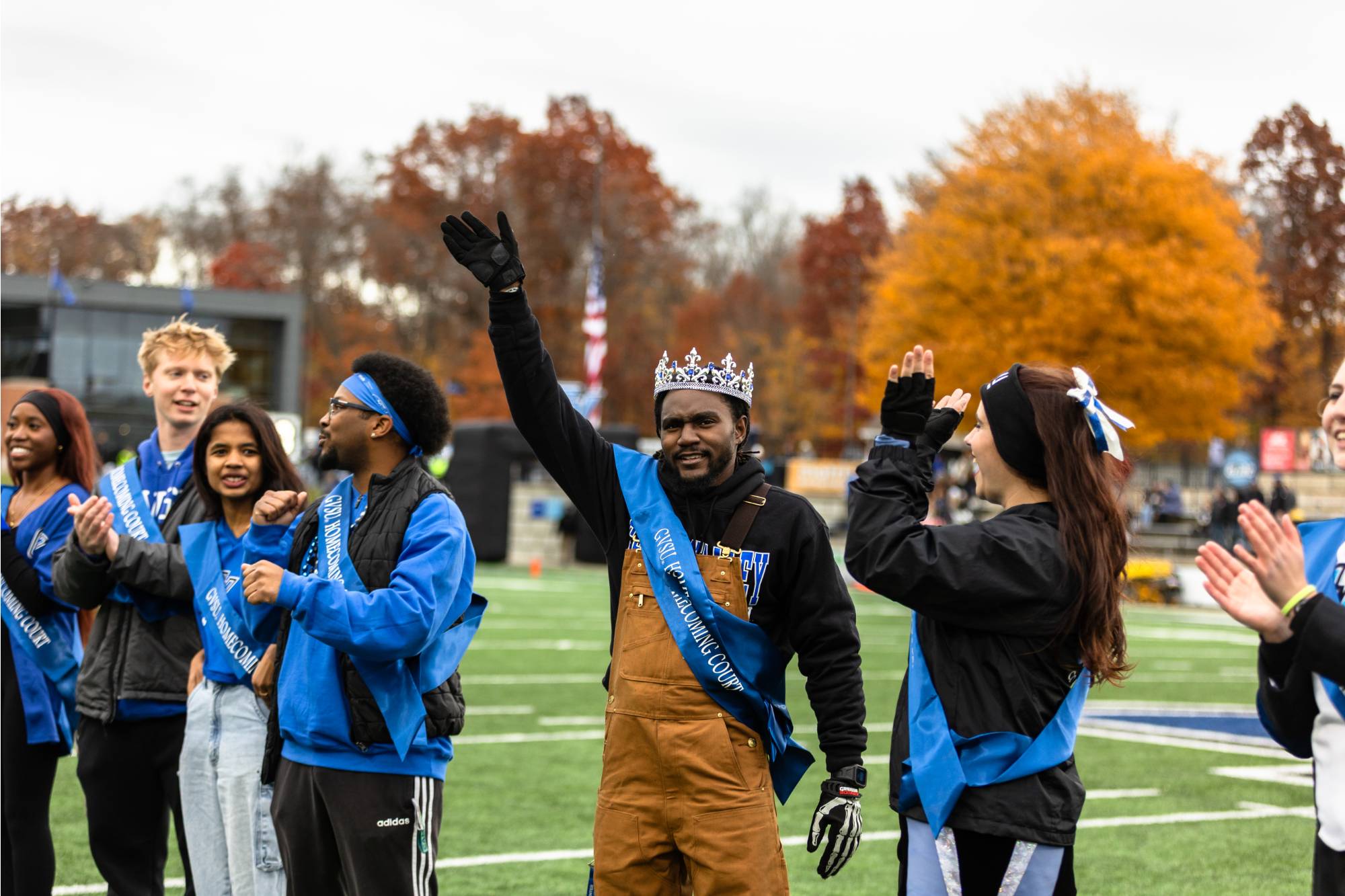 students standing on the football field waving at crowd